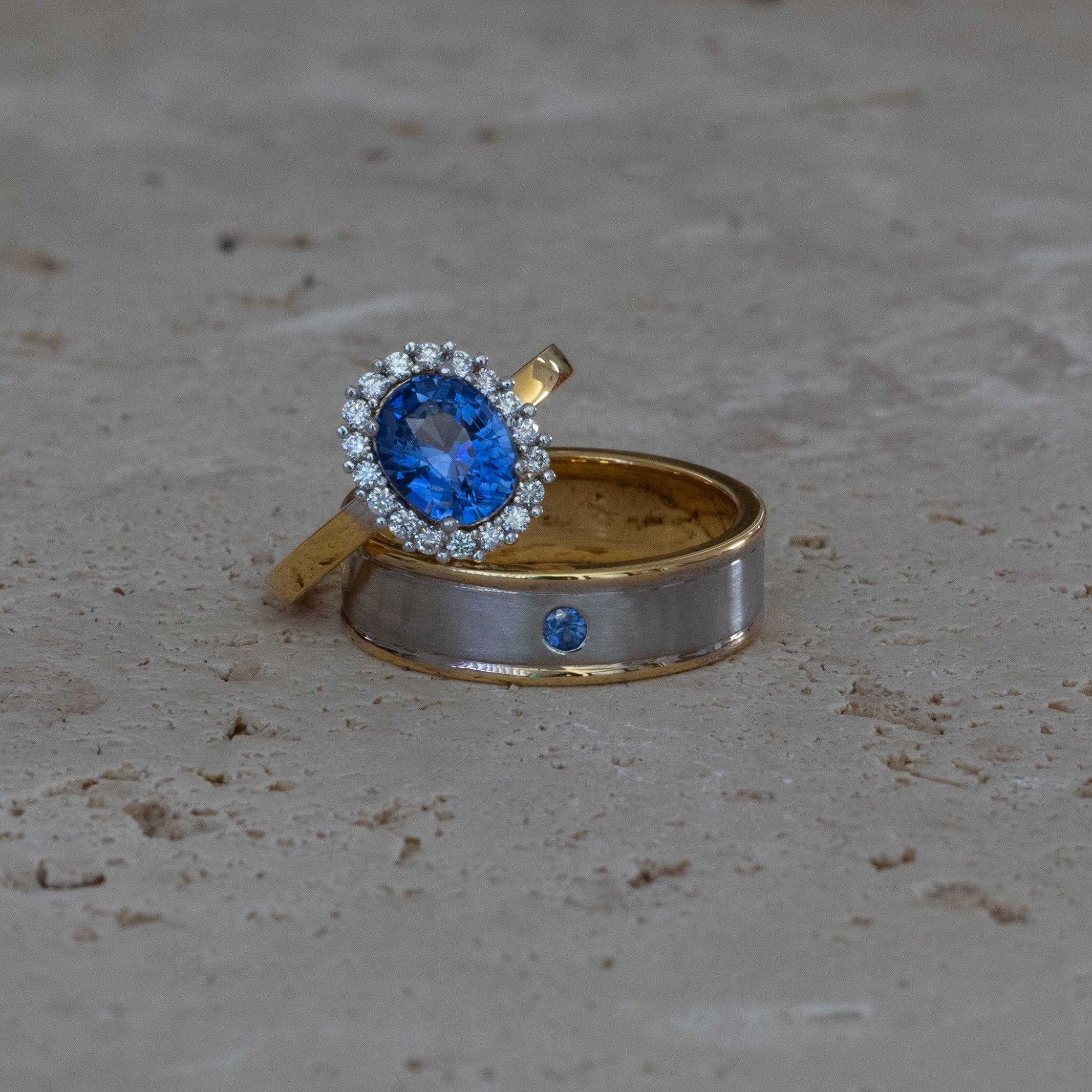 Gold and silver ring with blue gemstone on a concrete surface